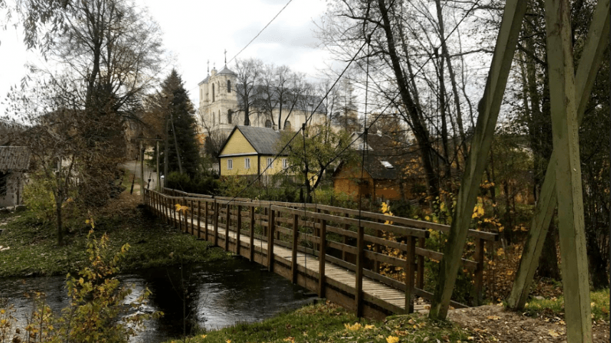 Wooden walkway extending over the still surface of Lake Antalieptė at sunset