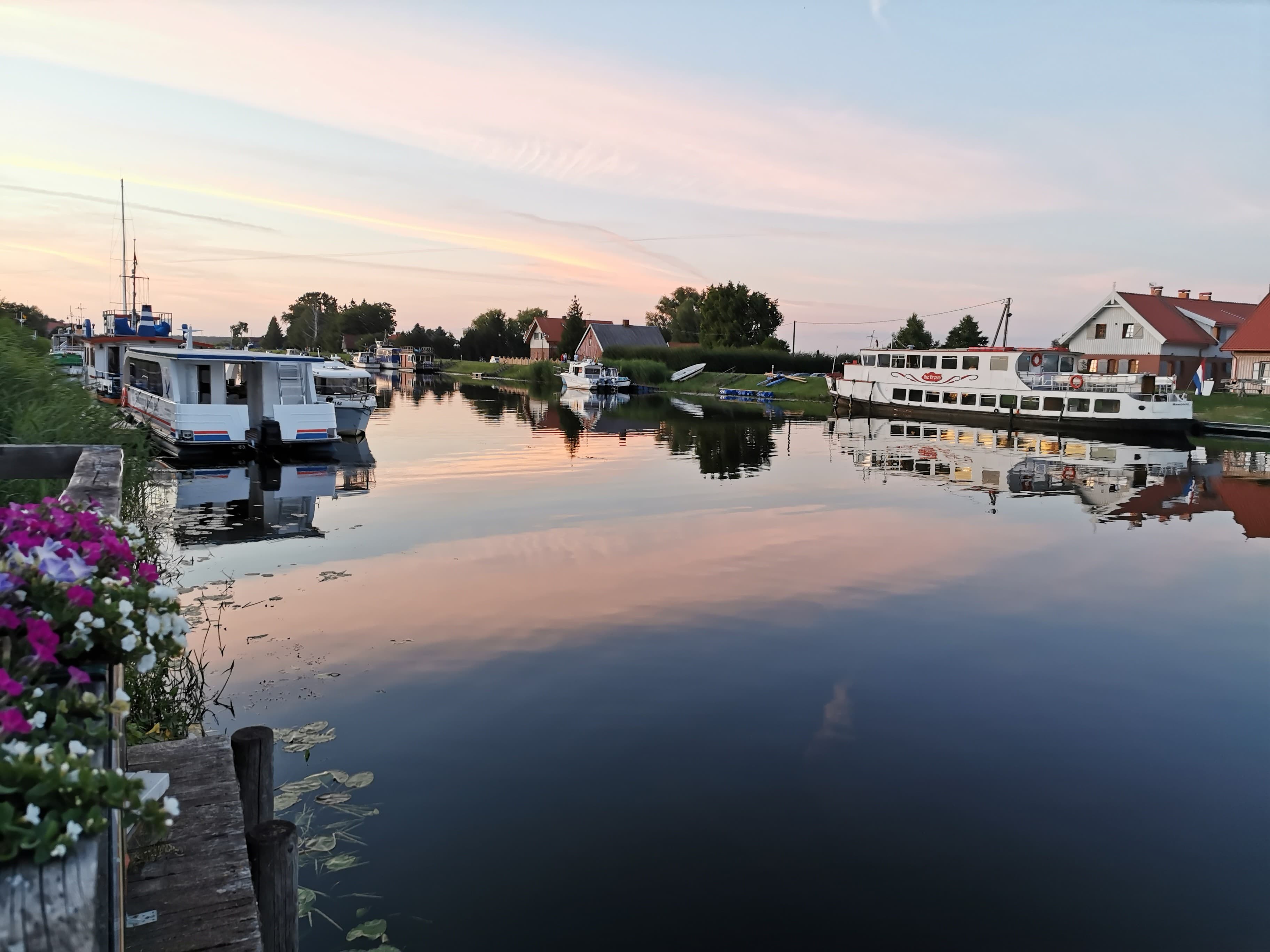 Houses lining both banks of the Minija River with boats moored at doorsteps