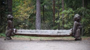 Large wooden witch sculpture looming among pine trees on Witch Hill